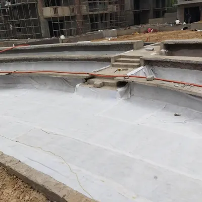 The first step in creating a rooftop or podium garden is waterproofing. Here, we are laying a protective geotextile membrane over the concrete structure.