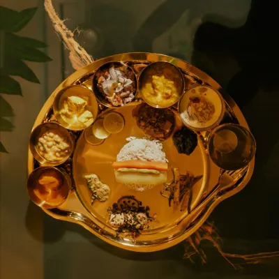 A top-down view of the Royal Manipuri Chakluk. The golden brassware makes the vibrant colors of the vegetarian dishes pop, creating a truly regal dining experience.