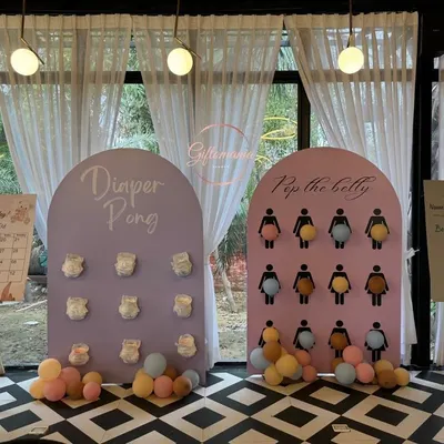 A full view of the baby shower game station, featuring 'Diaper Pong' and 'Pop the Belly' boards in a pastel color scheme. These games are always a huge hit with guests.