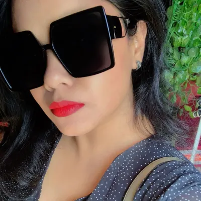 A bold red lip and oversized square sunglasses are a power combination. This close-up shows how accessories and makeup create a 'main character' vibe.