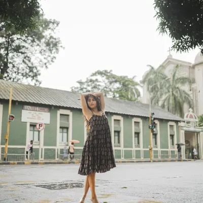 A full-length shot of a model on a quiet Mumbai street, using the urban architecture and overcast sky to create an atmospheric fashion photo.
