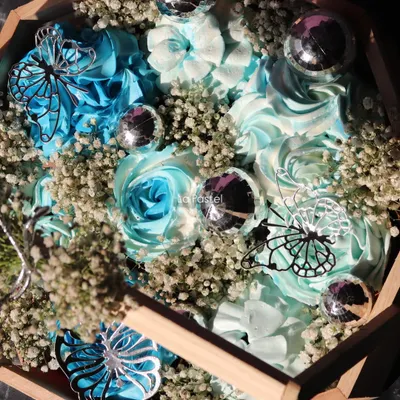 A close-up of the blue-themed cupcake basket, showing the detailed frosting work, silver butterflies, and disco ball accents.
