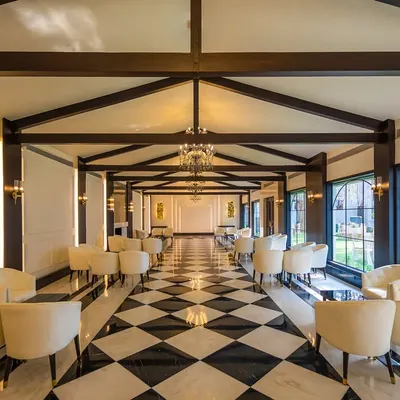 The completed Gallops banquet hall, set up for an event. The combination of the checkered marble floor, vaulted ceiling with dark wood beams, and classic white chairs creates a sophisticated and airy atmosphere, ready to be customized for any occasion.
