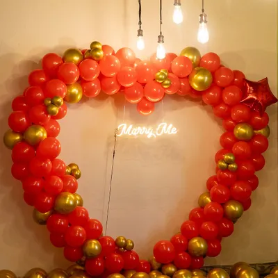 The perfect setting to pop the big question. We created this large heart-shaped balloon arch in red and gold with a 'Marry Me' neon sign to make the moment truly unforgettable.