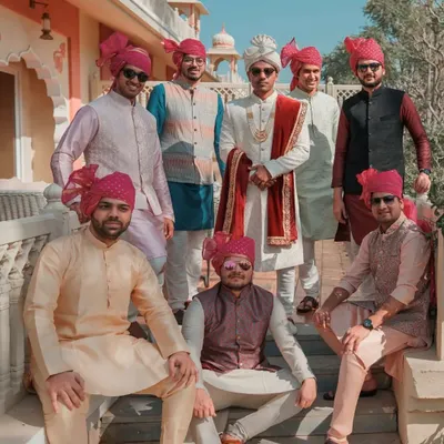 The groom and his groomsmen posing for a stylish group photo in their traditional Indian attire and vibrant pink turbans. A perfect shot of the groom's squad.
