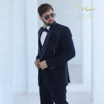 A detailed shot of our custom navy blue tuxedo. The shawl lapel and shoulder are adorned with intricate floral beadwork, adding a layer of texture and sophistication to the deep navy fabric.