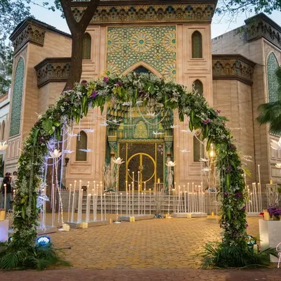 The entrance to this 25th-anniversary party was designed to be magical. A lush floral archway welcomed guests, leading them down a path lined with beautiful illuminated lotus flowers towards the magnificent venue.