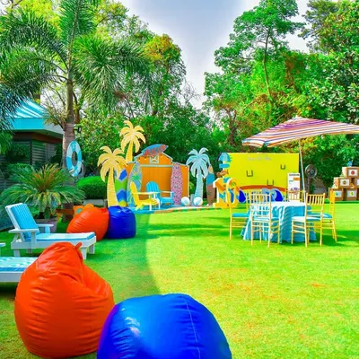 This wide shot showcases a full outdoor summer beach party setup. I used the entire lawn, setting up distinct zones for lounging, photos, and activities, all unified by a vibrant, tropical colour scheme.