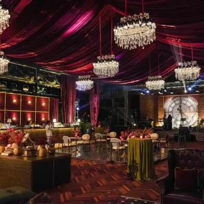 A wide view of our speakeasy-themed reception, showcasing the dramatic ceiling treatment with burgundy velvet and an array of crystal chandeliers. We handle the entire production, from structural rigging to lighting design.