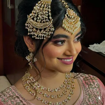 A perfect North Indian engagement look. This bride is wearing a beautiful pink outfit with elaborate kundan and pearl jewellery, including a statement passa and maang tikka. The makeup is soft and rosy to match.