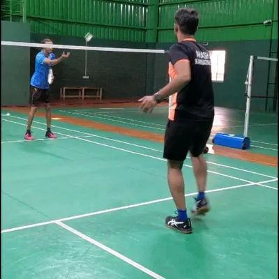A coach provides one on one instruction during a practice session. I ensure players receive personalized feedback to help them master basic badminton strokes and improve their game.