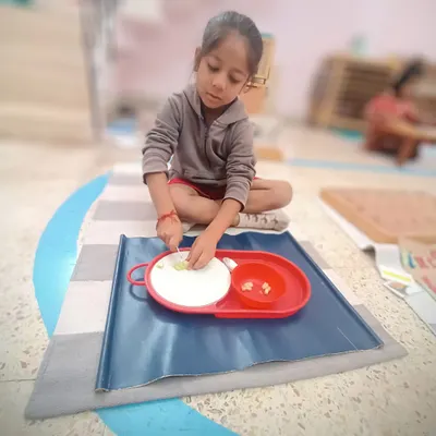Using a child-safe knife, this student is carefully cutting a cucumber. This practical life activity is fantastic for developing fine motor skills, concentration, and the independence that comes from preparing one's own food.