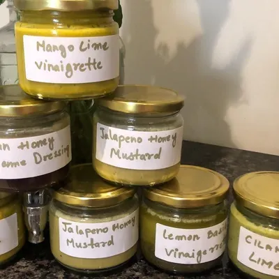 A selection of my homemade fresh salad dressings. You can see the variety, from Mango Lime Vinaigrette to Jalapeño Honey Mustard, all clearly labelled and ready to go.