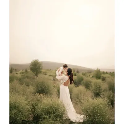 A mother lifts her child towards the sky in a wide, open field. This image captures a feeling of freedom, joy, and boundless love, with the vast landscape emphasizing the grand scale of a mother's affection.