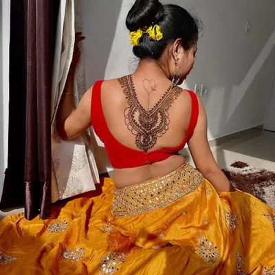A client showcasing a beautiful henna design on her back. This piece is designed to look like an elegant necklace, perfect for a low-back blouse.