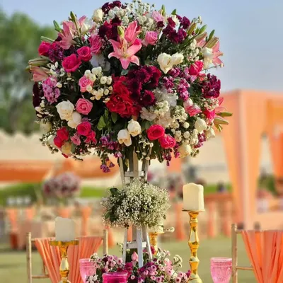 A magnificent and tall floral centerpiece, perfect for adding height and drama to guest tables. The mix of pinks, whites, and deep reds creates a rich and romantic look.
