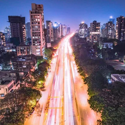 A long exposure shot from a drone, looking down a major road in Mumbai, turning the vehicle lights into brilliant white and red streaks.