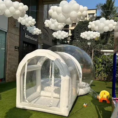 The transparent bubble house with its attached entrance tunnel. This design allows for easy entry and exit while keeping the balloons inside the main dome.