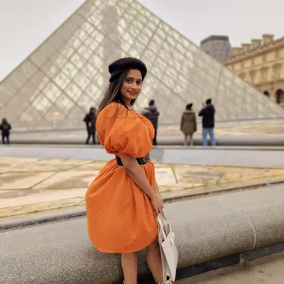 Our client looking absolutely radiant in our custom orange puff-sleeve dress while visiting the Louvre in Paris. We designed this dress to be both comfortable for exploring and stylish enough for a photoshoot.