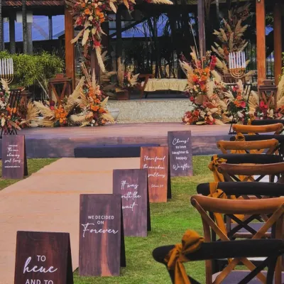 The aisle view of a beautiful boho-themed wedding. I used custom wooden signs with romantic quotes to guide the couple's path to a stunning mandap decorated with pampas grass and autumnal flowers.