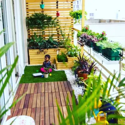We transformed this apartment balcony into a safe and fun green space for the family. The design includes a mix of wooden decking and artificial grass, with raised planters and hanging pots to maximize the greenery.