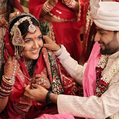 A happy moment from a Marwadi wedding ceremony. The bride's subtle makeup and radiant smile shine through, complementing her traditional red attire and jewelry.