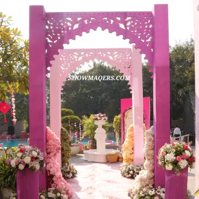 A grand entrance for a pink themed Haldi ceremony, featuring intricately cut magenta arches and lush floral arrangements, creating a stunning poolside welcome.