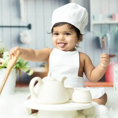 Our little chef is ready to cook up some fun. This themed photoshoot captures a baby's playful side with a chef hat and kitchen props.