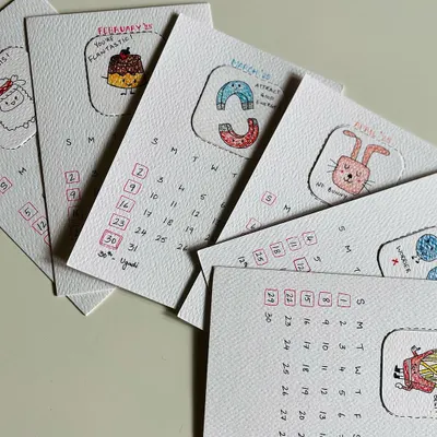 A first look at the pages for the 2025 calendar, fanned out to show the different hand-drawn illustrations. Each one is a little piece of art.