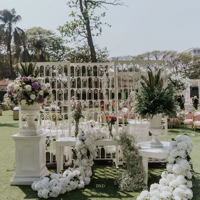 A beautiful photo corner created with white floral arrangements and intricate lattice screens. These details provided a perfect backdrop for guest photos at a vintage-themed wedding.