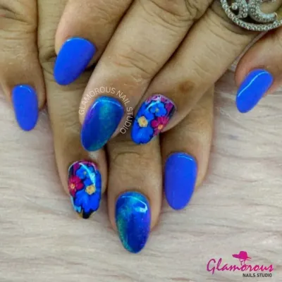 A stunning contrast of electric blue nails and intricate, hand-painted floral art. The accent nails feature a bouquet of pink and blue flowers, showcasing our detailed brushwork.