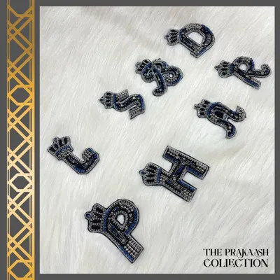A collection of hand-embroidered initial patches in a regal font, topped with a crown. Crafted with black and silver beads, these are perfect for adding a personalized, crest-like touch to your belongings.