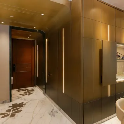 This view of the entryway shows the seamless integration of a concealed bar cabinet within the brass paneling. The design balances elegance and functionality, adding a layer of subtle intrigue.