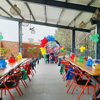 An Avengers-themed party setup in an outdoor venue, showing the main backdrop and themed table arrangements for guests.