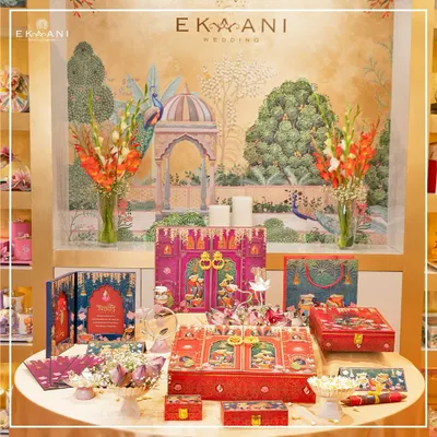 A complete wedding suite from my Pichwai-themed collection, set against a backdrop of heritage art. This display shows how I curate every element, from large hamper boxes to matching gift bags, to create a cohesive and opulent wedding story.