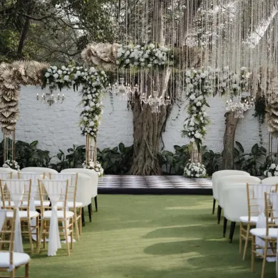 This stunning outdoor wedding ceremony was set against a beautiful old tree, which we framed with an arch of white flowers, greenery, and delicate chandeliers. The checkered dance floor and elegant seating completed this timeless and classic wedding design.