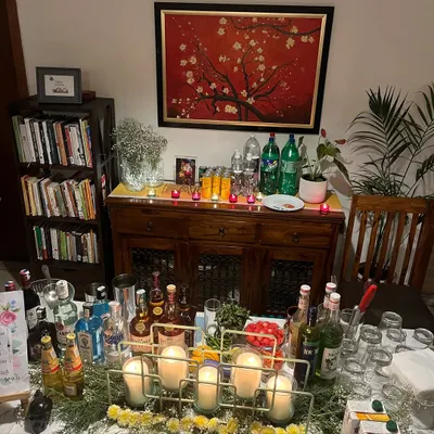 A perfect example of a home bar setup. We transformed a living room sideboard into a fully functional bar, complete with a wide selection of spirits, mixers, glassware, and candlelit decor for a cozy house party.