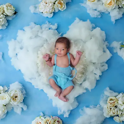 A sweet and serene newborn portrait. I created this image by placing the baby on a fluffy cloud heart, using a soft blue sky and white flowers for a heavenly feel.