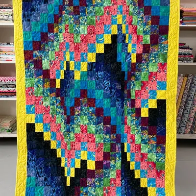 A bright and energetic Bargello quilt. The wave-like pattern is created by sewing strips of fabric, and the vibrant colors give it a dynamic, modern feel.