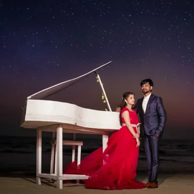 A magical pre-wedding night shoot on the beach. This couple used a piano prop under a starry sky, with the red trail gown adding a touch of vibrant, romantic color.