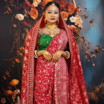 A full-length view of a traditional Bengali bride, showcasing the rich red Banarasi saree and the unique way of draping the veil.