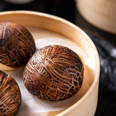 Our signature Mushroom Bao Buns are a work of art. The bun is crafted to resemble a shiitake mushroom and filled with a rich, umami-packed filling, served steaming in a traditional bamboo basket.