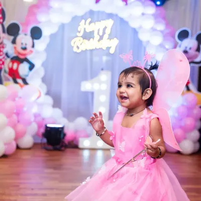 A delightful shot of the birthday girl in her pink fairy costume, smiling with excitement amidst the party decorations.