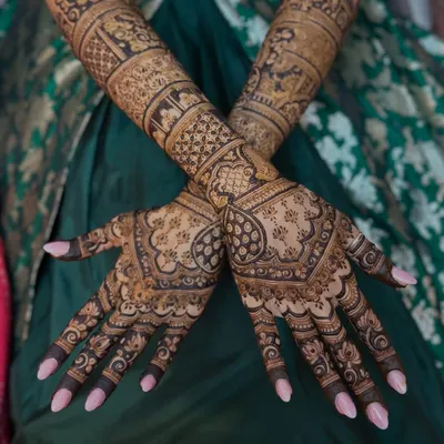 A stunning full-sleeve bridal mehendi that combines geometric patterns with traditional figures. This design is for the bride who wants to make a grand statement.