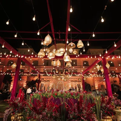 The central lounge of the Moroccan-themed sangeet, where a cluster of brass lamps and filament bulbs hung above lush floral arrangements. This space was the heart of the party, designed for cozy conversations and vibrant celebration.