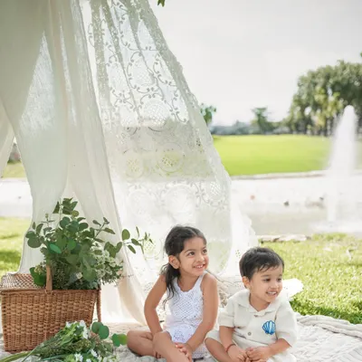 A sweet moment between siblings during an outdoor picnic photoshoot. I set up this lace tent and wicker basket to create a dreamy, boho atmosphere right in the park.