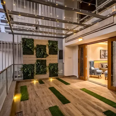 A spacious patio area that seamlessly connects with the indoors. We used a vertical garden, wood-like floor tiles with grass inserts, and charming string lights to create a perfect space for evening relaxation.