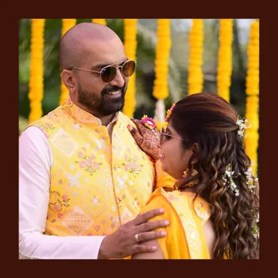 A happy couple during their Haldi ceremony. The groom's custom yellow waistcoat with floral embroidery is perfectly in sync with the bride's yellow saree, creating a bright and joyful look.