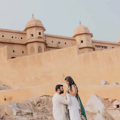 A regal pre-wedding portrait at Amer Fort in Jaipur. The groom-to-be gets on one knee, creating a timeless and romantic photograph against the backdrop of historic architecture.