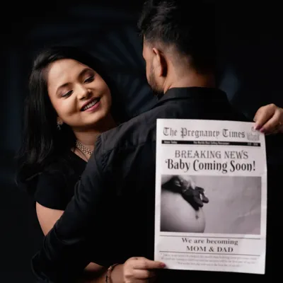 A fun and creative pregnancy announcement. The couple uses a custom "The Pregnancy Times" newspaper prop to share their exciting news in a memorable way.